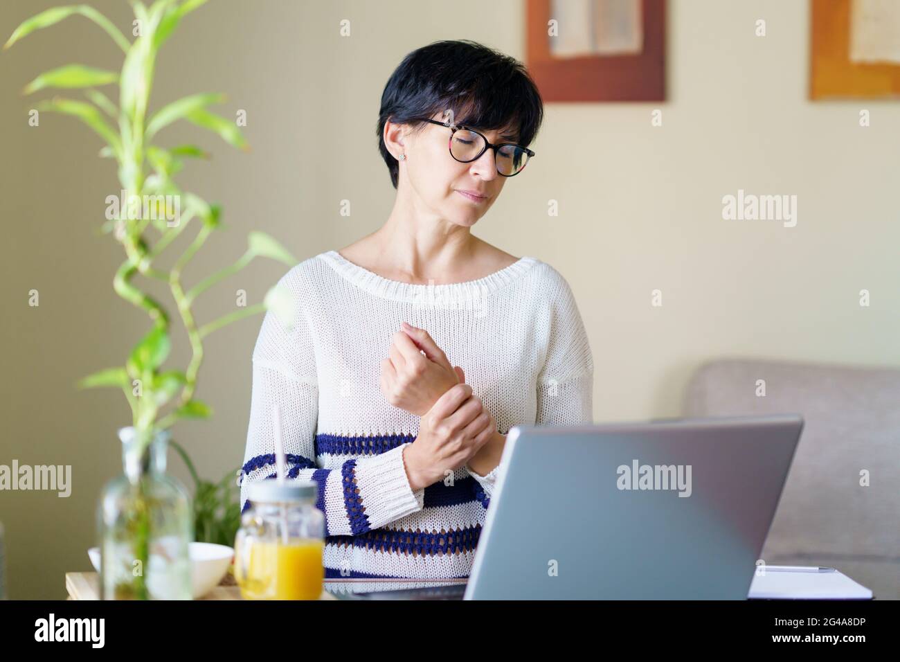 Femme teleworking de la maison avec douleur de poignet ayant un massage pour se reposer. Banque D'Images