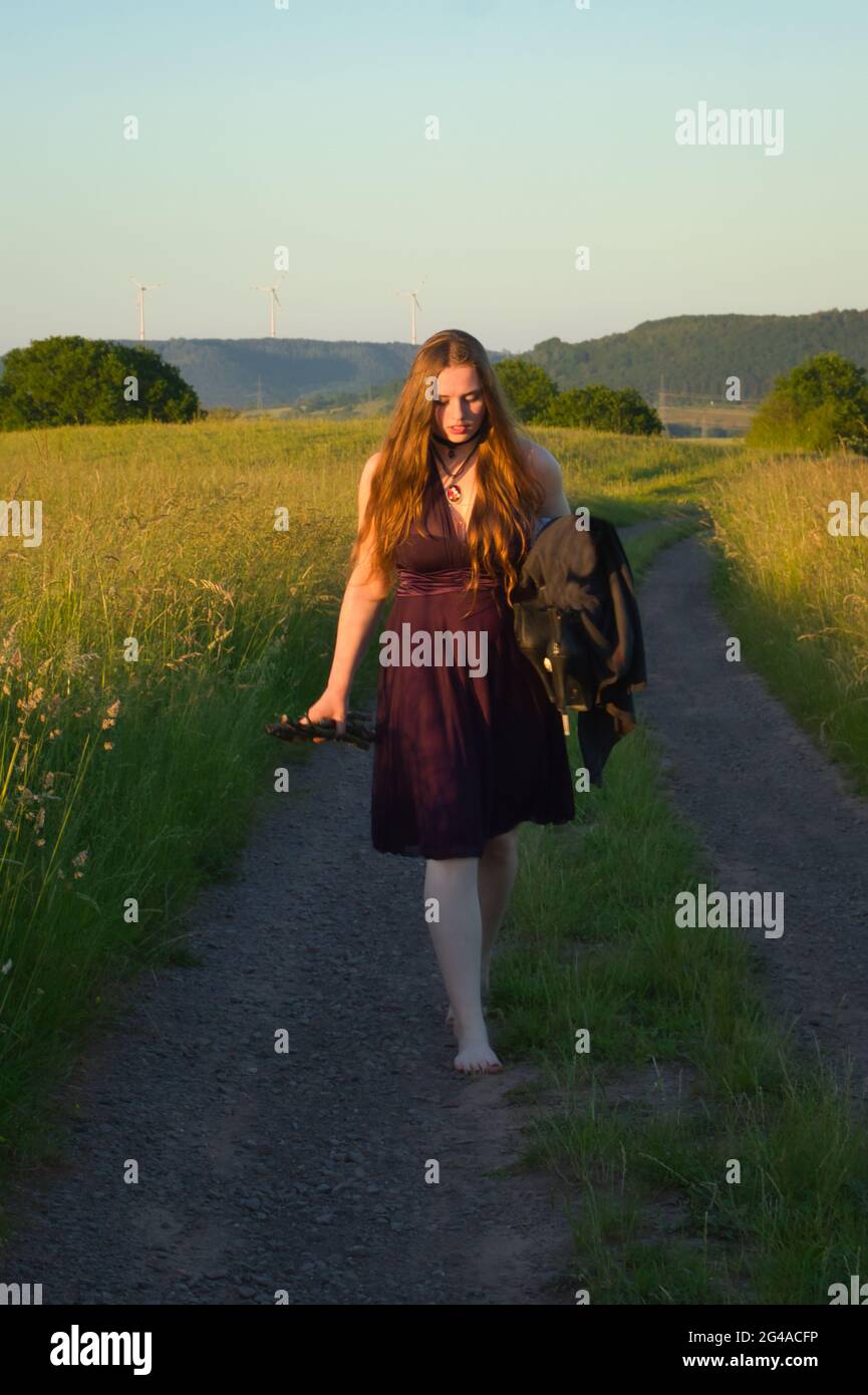 Une adolescente marchant pieds nus sur une route de campagne dans la campagne rurale de l'Allemagne pendant une nuit de printemps. Banque D'Images