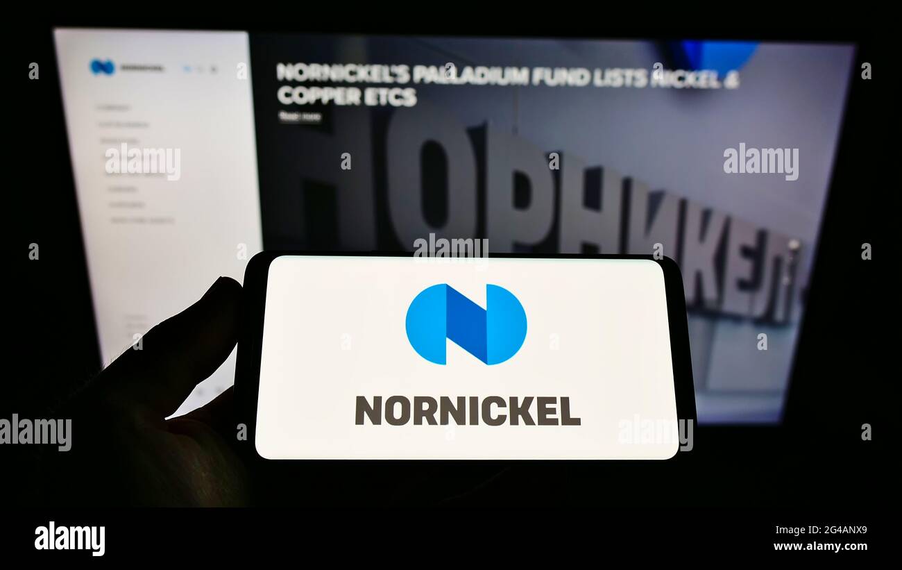 Personne tenant un téléphone portable avec le logo de la société minière russe Norilsk Nickel (Nornickel) à l'écran devant la page Web. Mise au point sur l'affichage du téléphone. Banque D'Images