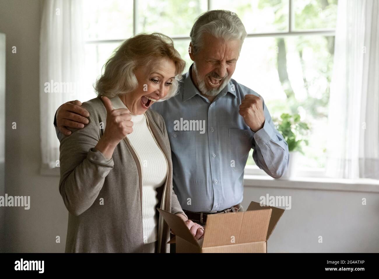 Un vieux couple surjoyeux triomphant avec une bonne commande en ligne Banque D'Images