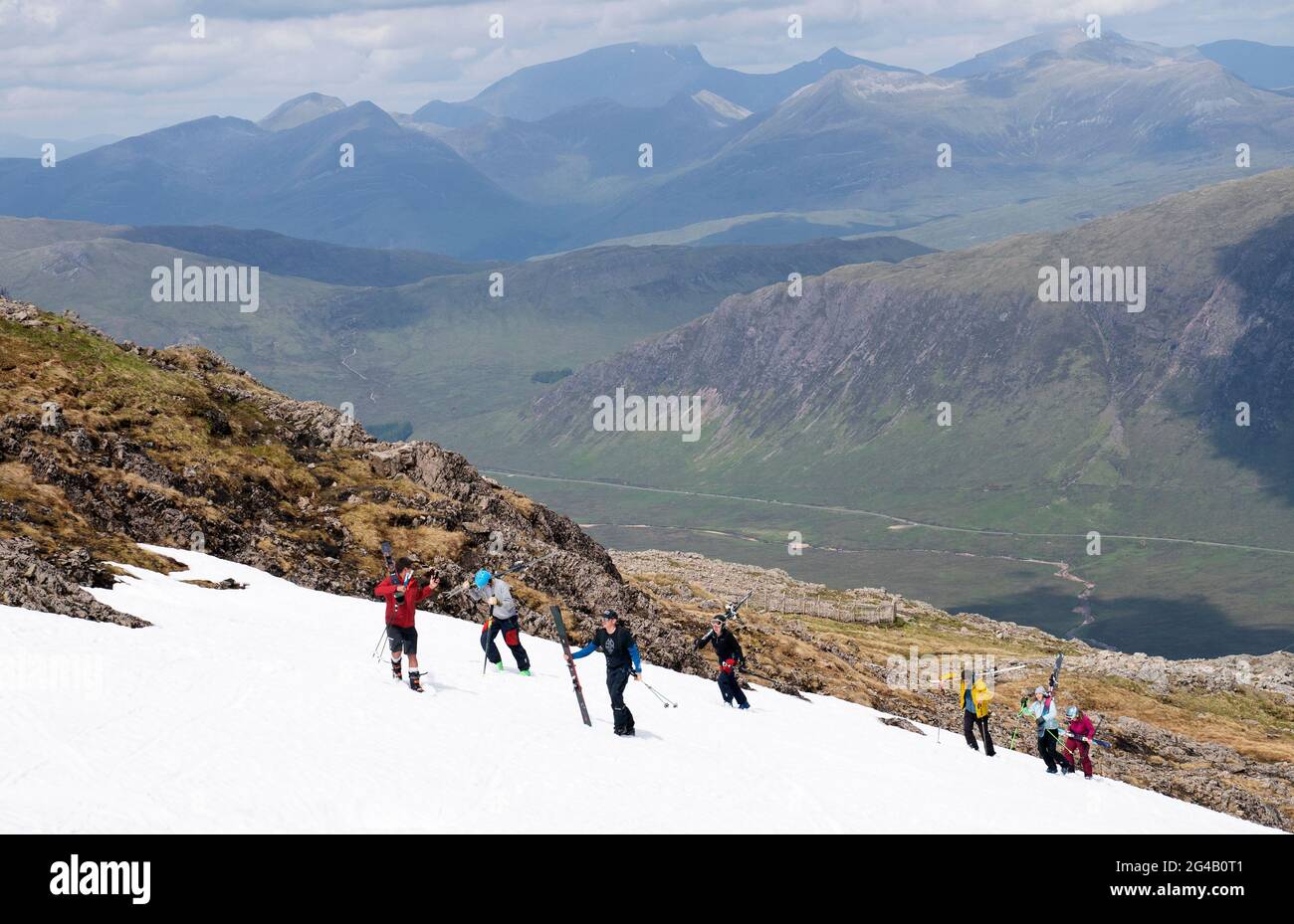 Les skieurs et les snowboardeurs grimpent jusqu'aux restes de neige sur Meall a'Bhuiridh à Glencoe pour prendre part au ski de milieu d'été. L'événement, organisé par le Glencoe Mountain Resort, se tient chaque année le week-end le plus proche du solstice d'été. Date de la photo: Dimanche 20 juin 2021. Banque D'Images