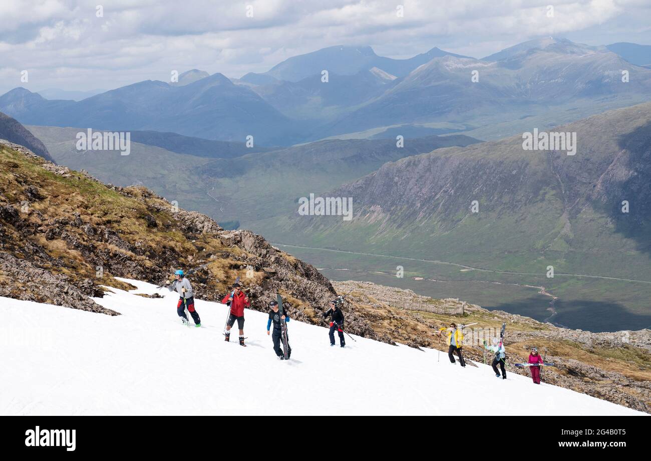 Les skieurs et les snowboardeurs grimpent jusqu'aux restes de neige sur Meall a'Bhuiridh à Glencoe pour prendre part au ski de milieu d'été. L'événement, organisé par le Glencoe Mountain Resort, se tient chaque année le week-end le plus proche du solstice d'été. Date de la photo: Dimanche 20 juin 2021. Banque D'Images