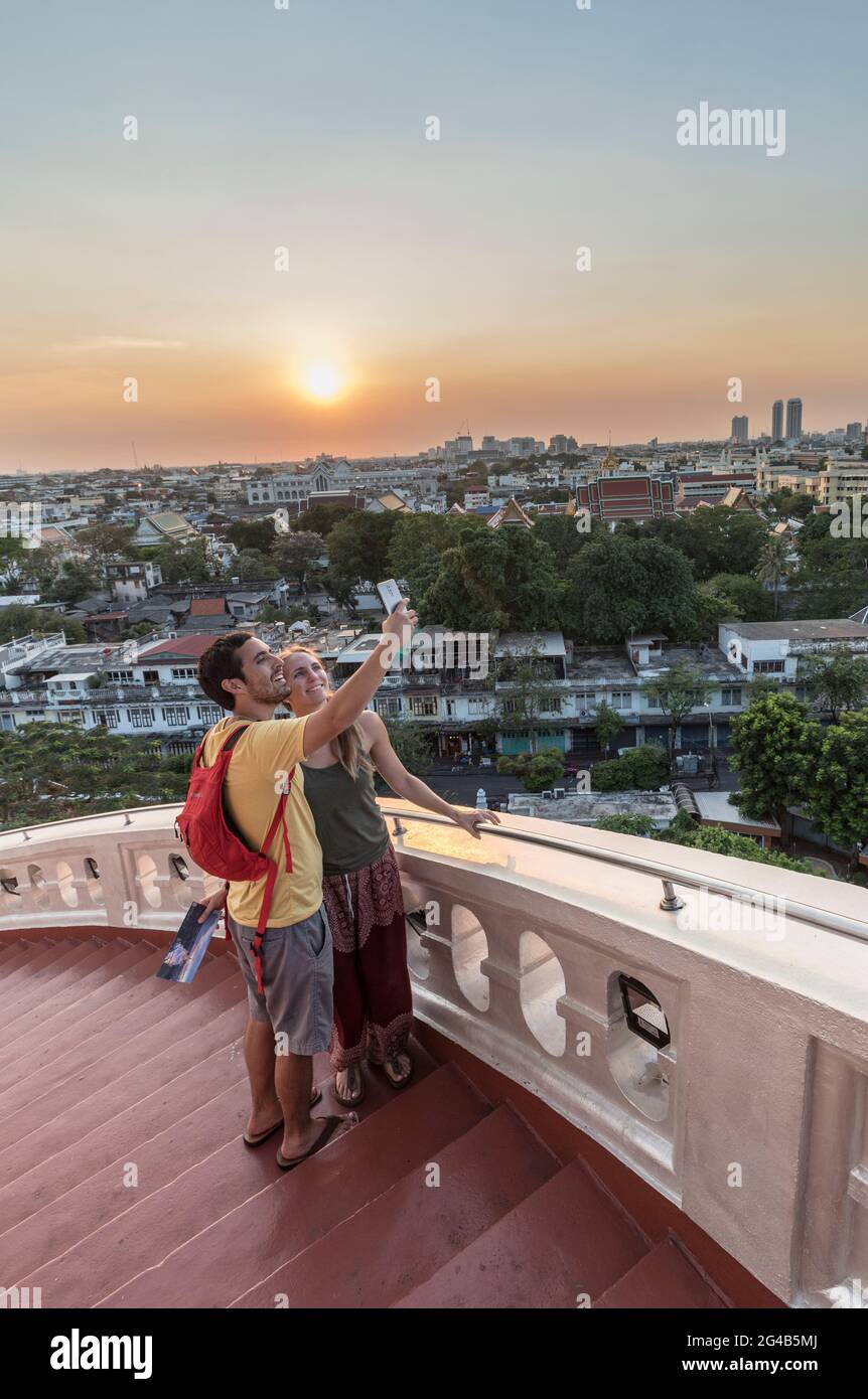 Couple prenant un selfie au coucher du soleil à Wat Saket, Golden Mountain, Temple de Srakesa, Bangkok, Thaïlande Banque D'Images