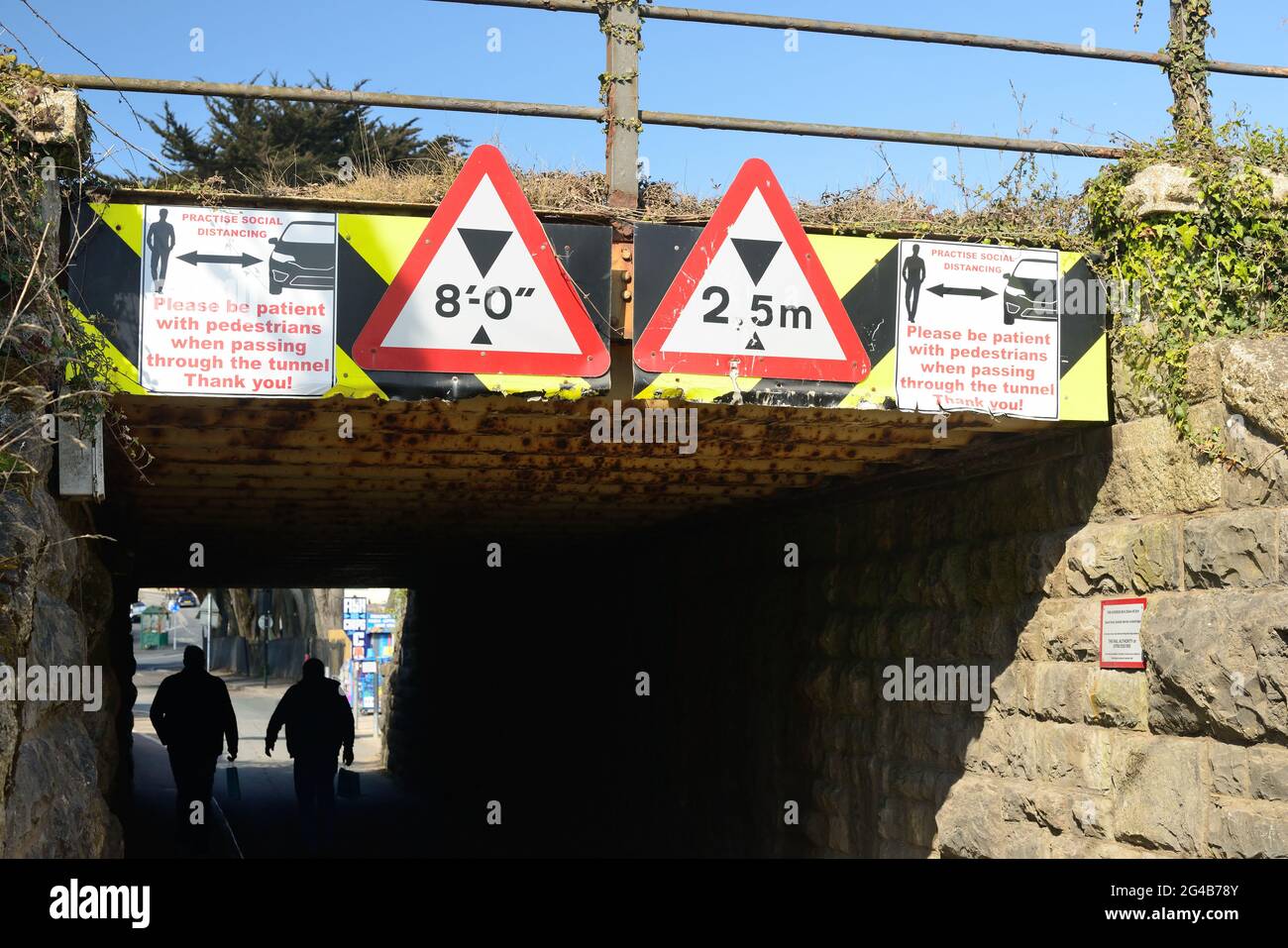 Signes de distanciation sociale sur un pont ferroviaire bas au-dessus d'un tunnel étroit partagé par les piétons et les véhicules à moteur. Banque D'Images