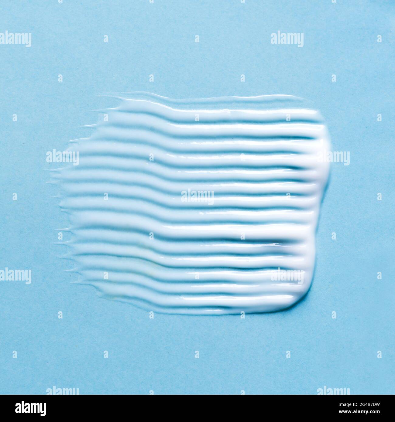 Nuance de baume pour le visage ou le corps sur fond bleu, gros plan. Trait de produit cosmétique. Banque D'Images