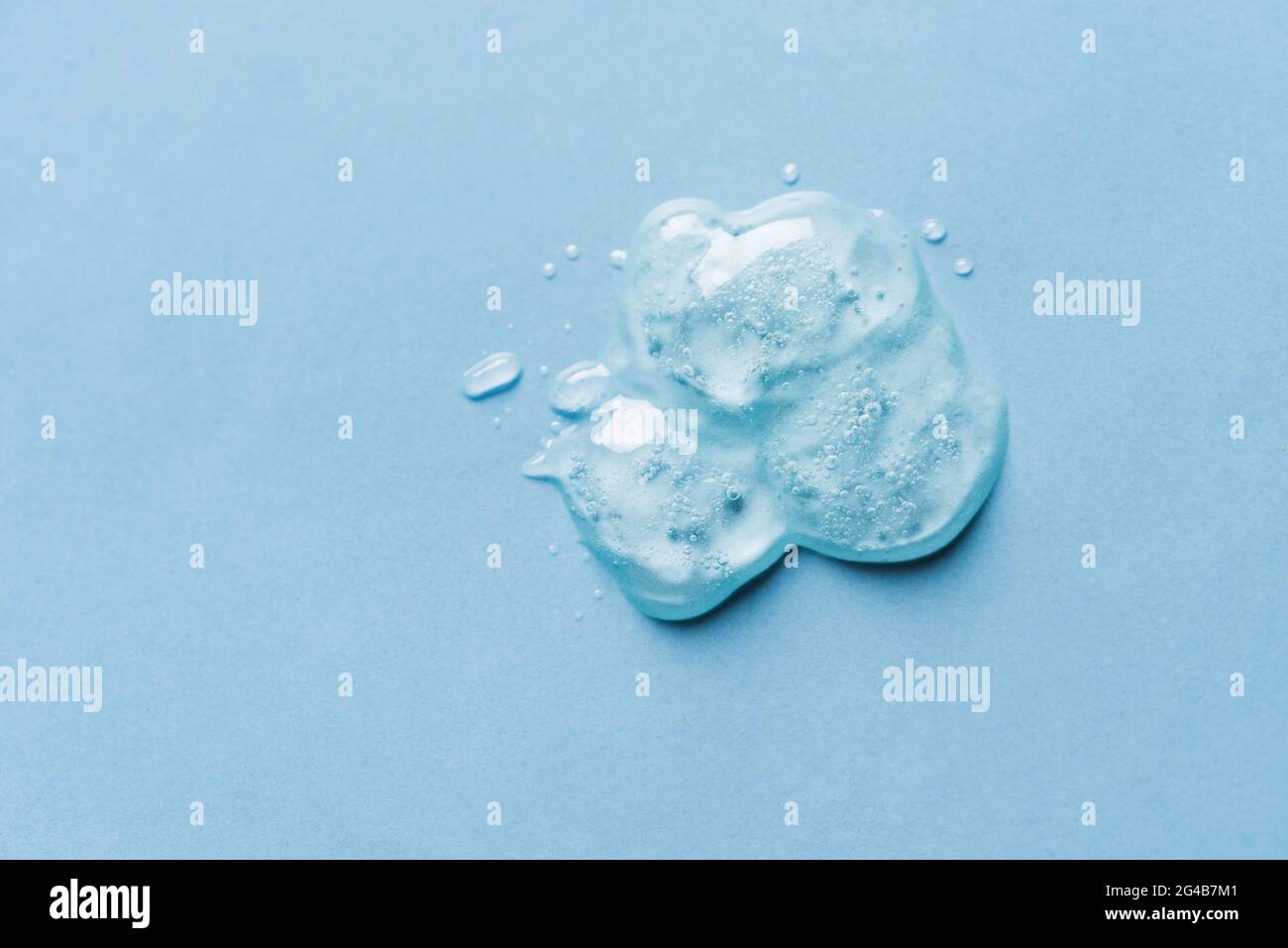 Texture gel sur fond bleu gros plan. Flaque de produit cosmétique en gel transparent. Banque D'Images