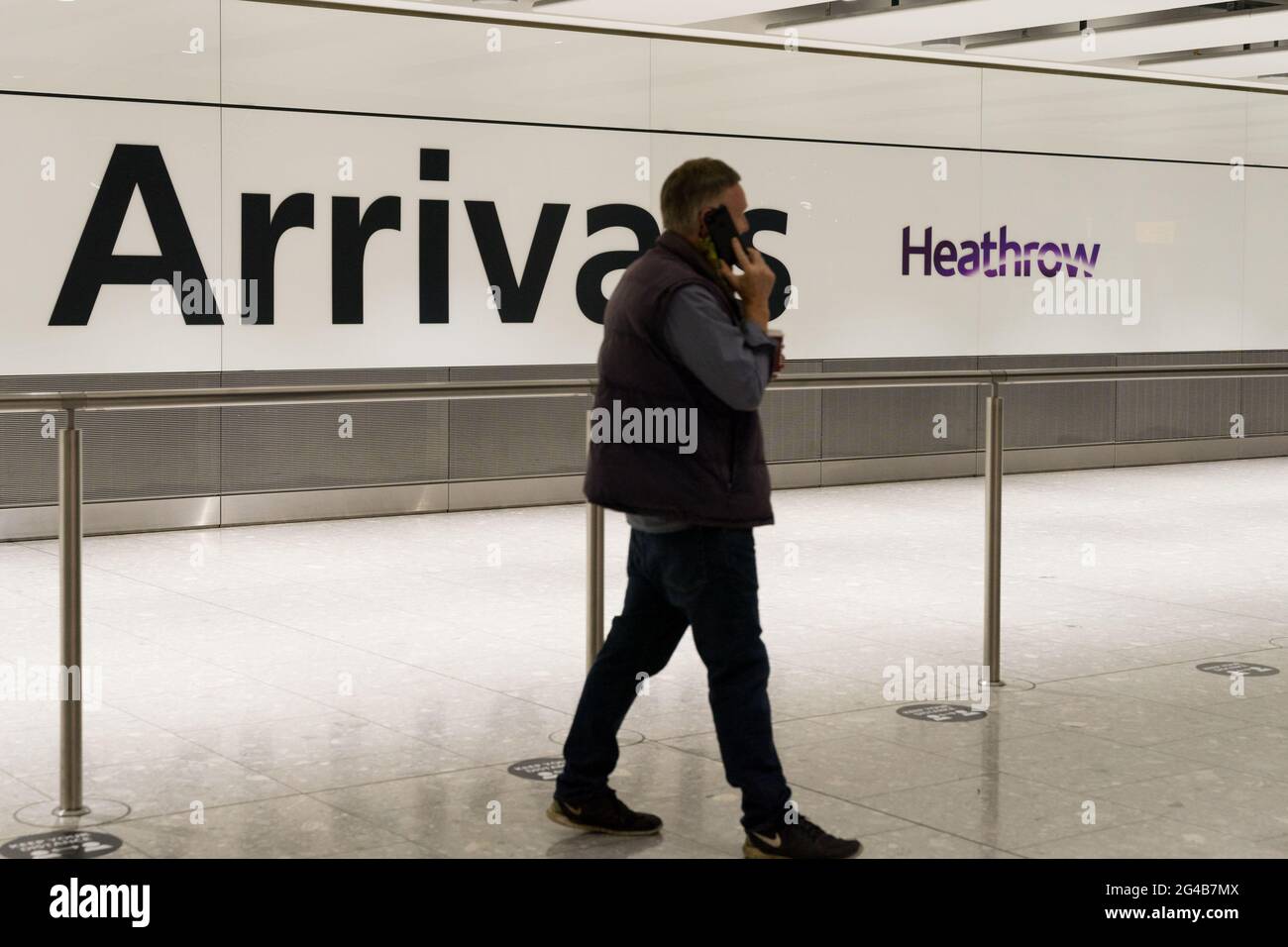 Homme au téléphone au hall des arrivées internationales de heathrow, Londres, Angleterre Banque D'Images