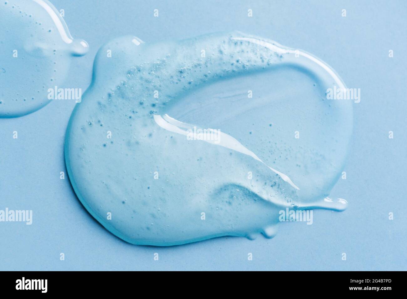 Texture gel sur fond bleu gros plan. Flaque de produit cosmétique en gel transparent. Banque D'Images