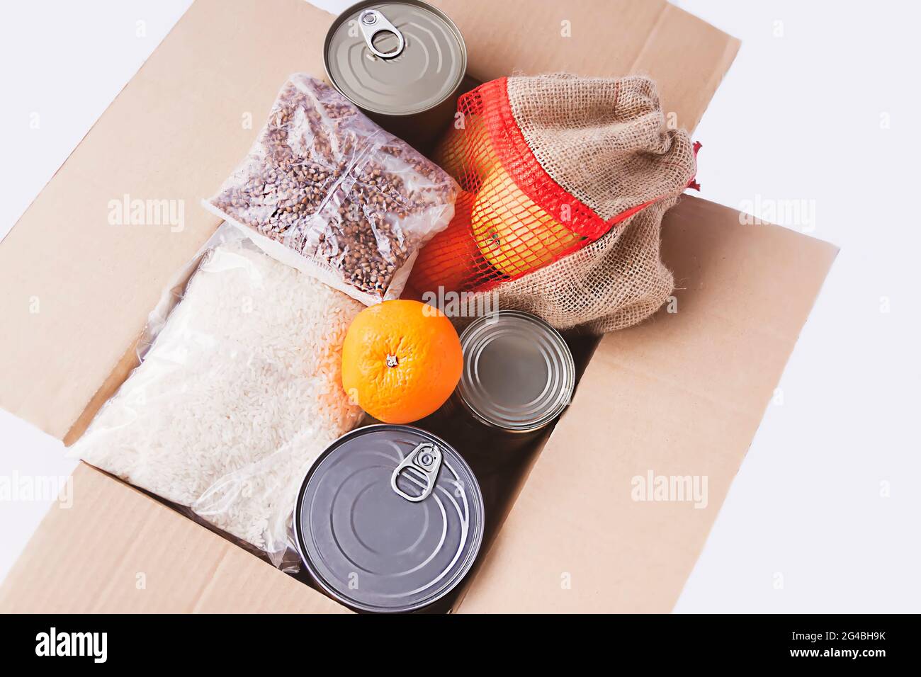 Boîtes de conserve, fruits frais aux pommes, sarrasin et riz dans une boîte en carton. Don d'aliments, thème de livraison. Banque D'Images