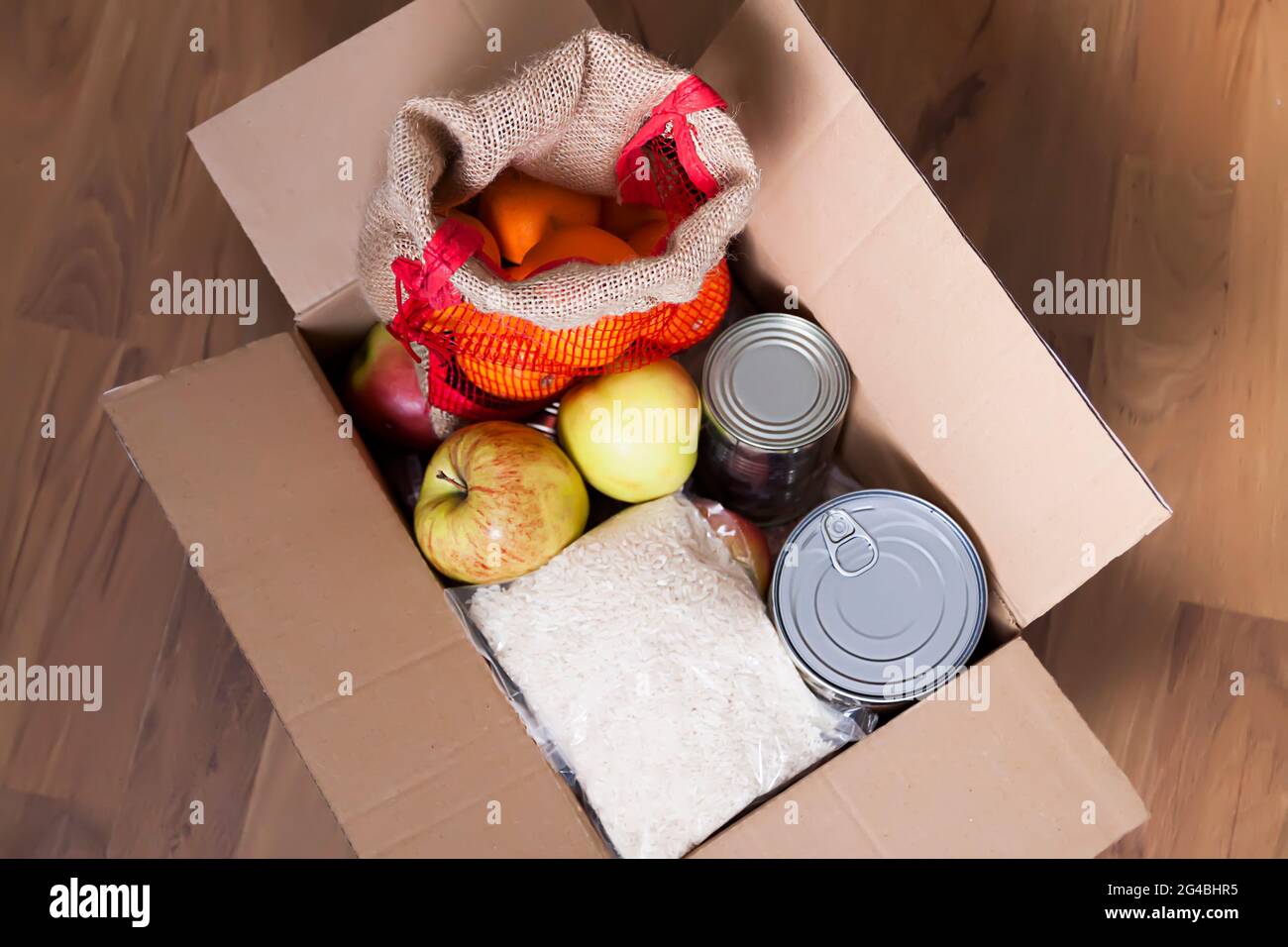 Boîtes de conserve, fruits frais aux pommes, sarrasin et riz dans une boîte en carton. Don d'aliments, thème de livraison. Banque D'Images