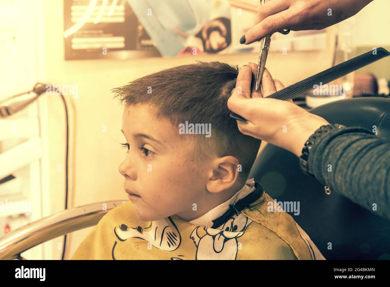 Petit garçon ayant une coupe de cheveux au salon de coiffure..enfants  coiffeur avec des ciseaux et le peigne est de couper petit garçon. Un  adorable garçon d'âge préscolaire Photo Stock - Alamy