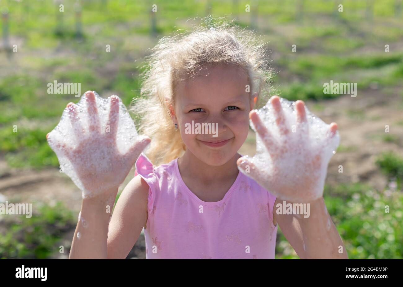 Portrait d'une petite fille heureuse montrant les mains avec de la mousse savonneuse Banque D'Images