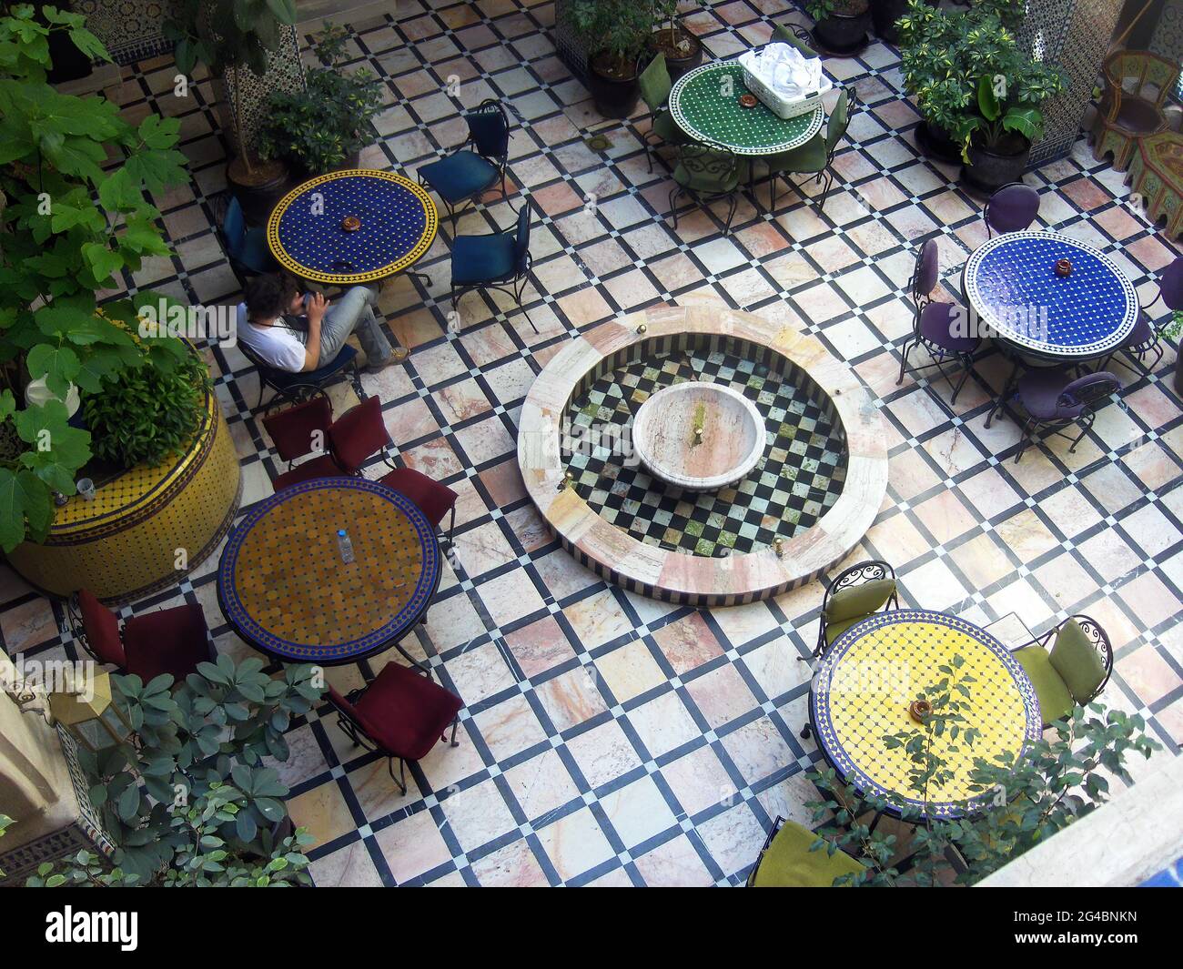 Fez, Maroc - 29 mars 2013: Un homme regardant son téléphone mobile assis dans un patio de design arabe. Banque D'Images