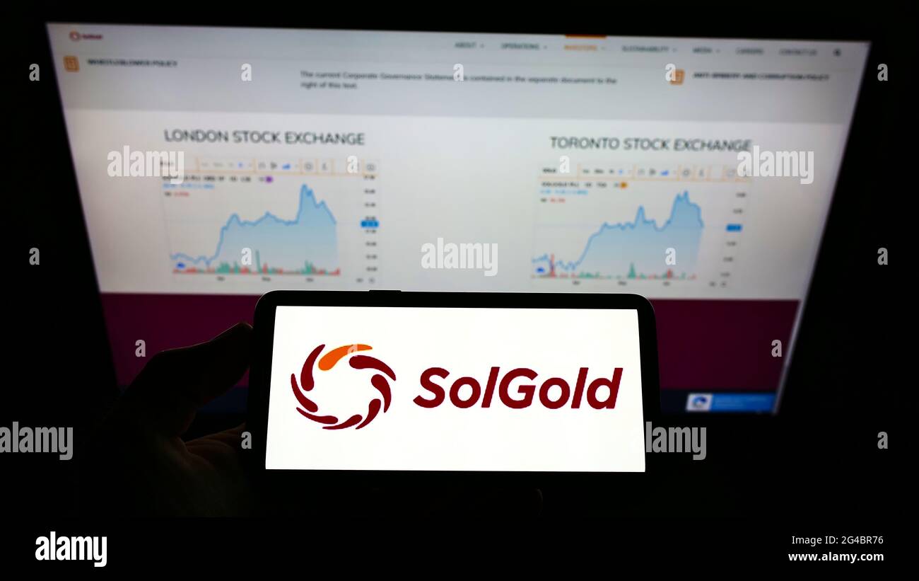 Personne détenant un smartphone avec le logo de la société minière australienne SolGold plc à l'écran devant le site Web. Mise au point sur l'affichage du téléphone. Banque D'Images