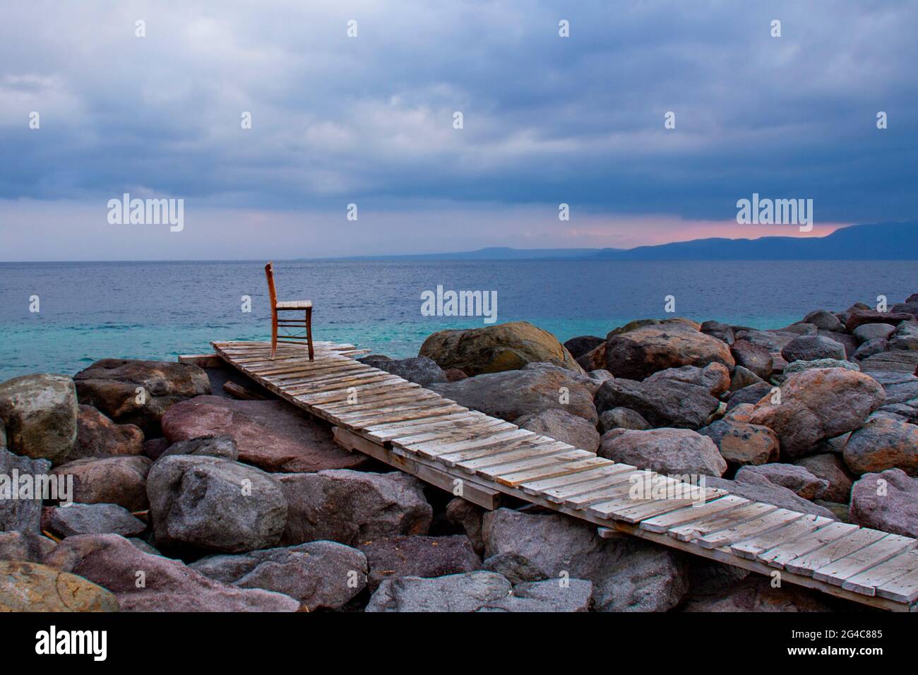 Chaise en bois sur la terrasse en bois sur les rochers le long de la mer Égée près de l'ancienne ville d'Assos en Turquie Banque D'Images
