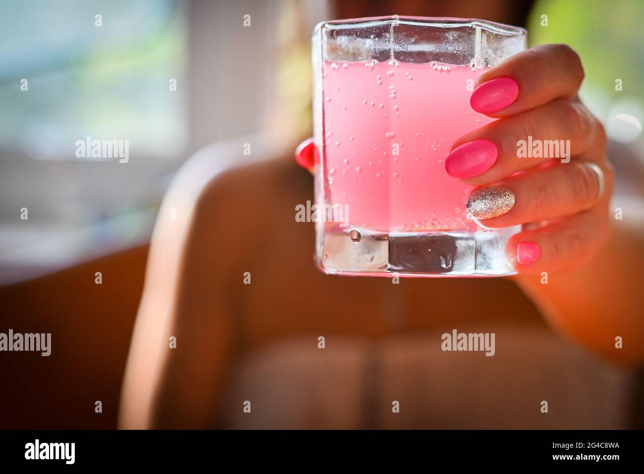 fille tenant un verre avec un cocktail rose Banque D'Images