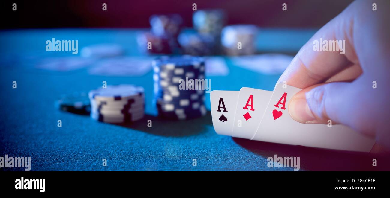 La main prend des cartes, trois as, joue au poker de casino. Arrière-plan avec espace de copie Banque D'Images