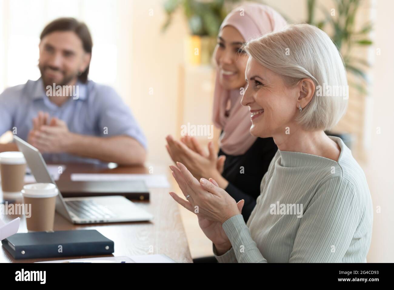 Sourire divers employés audience assis à table, applaudissant à la réunion Banque D'Images