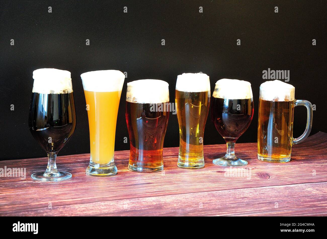 Six verres différents avec différents types de bière sont dans une rangée sur une table en bois. Gros plan. Banque D'Images