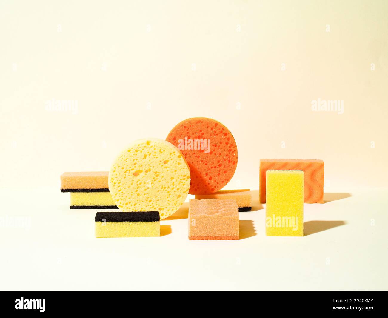 Éponges en caoutchouc mousse de différentes formes. Formes rondes et rectangulaires. Couleurs jaune et orange. Concept de nettoyage. Composition géométrique. Banque D'Images