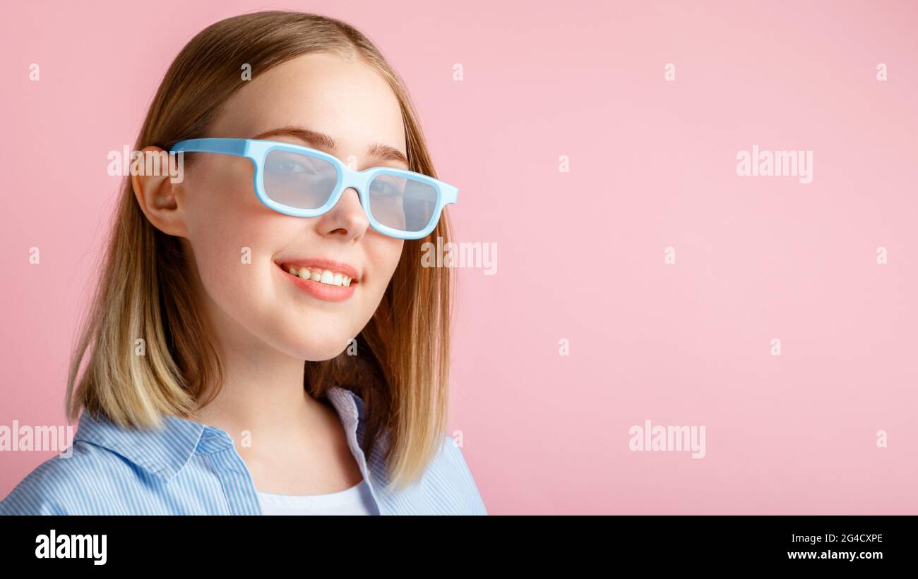 Jeune fille souriante portrait de la visionneuse de film dans des lunettes isolées sur fond rose couleur avec espace de copie. Jeune femme en lunettes de cinéma pour regarder Banque D'Images