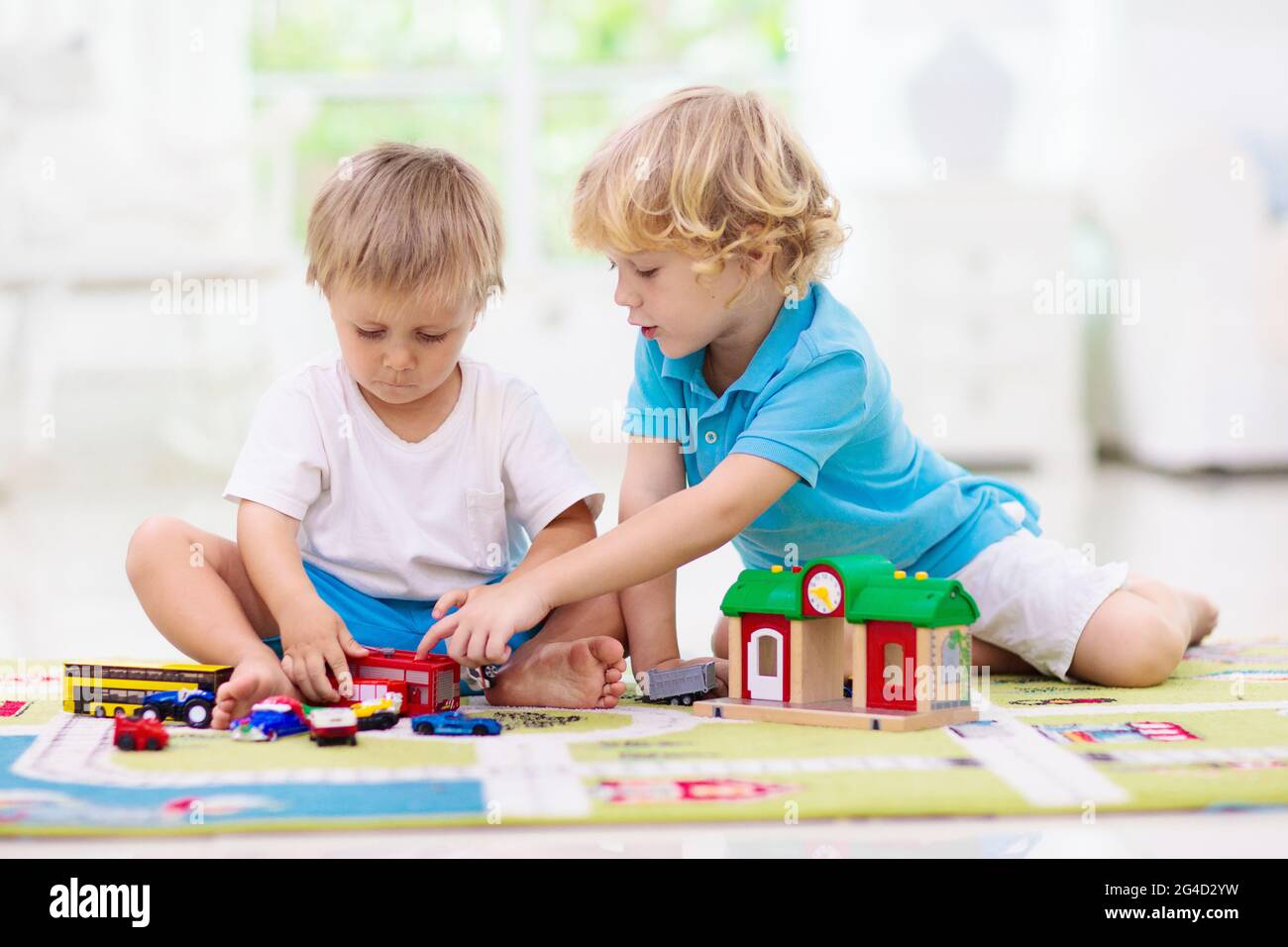 Petit garçon jouant des voitures de jouet sur le tapis de jeu. Jeune enfant  avec véhicule éducatif coloré et jouets de transport sur moquette. Plan de  la ville tapis. Conduite enfant Photo