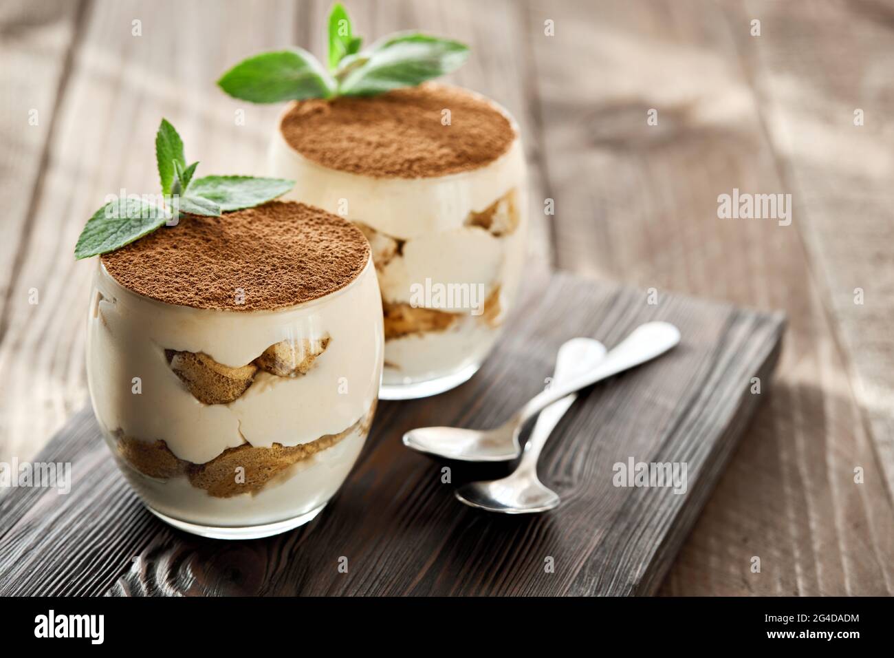 Dessert classique Tiramisu dans un verre sur une planche de bois par temps ensoleillé. Banque D'Images