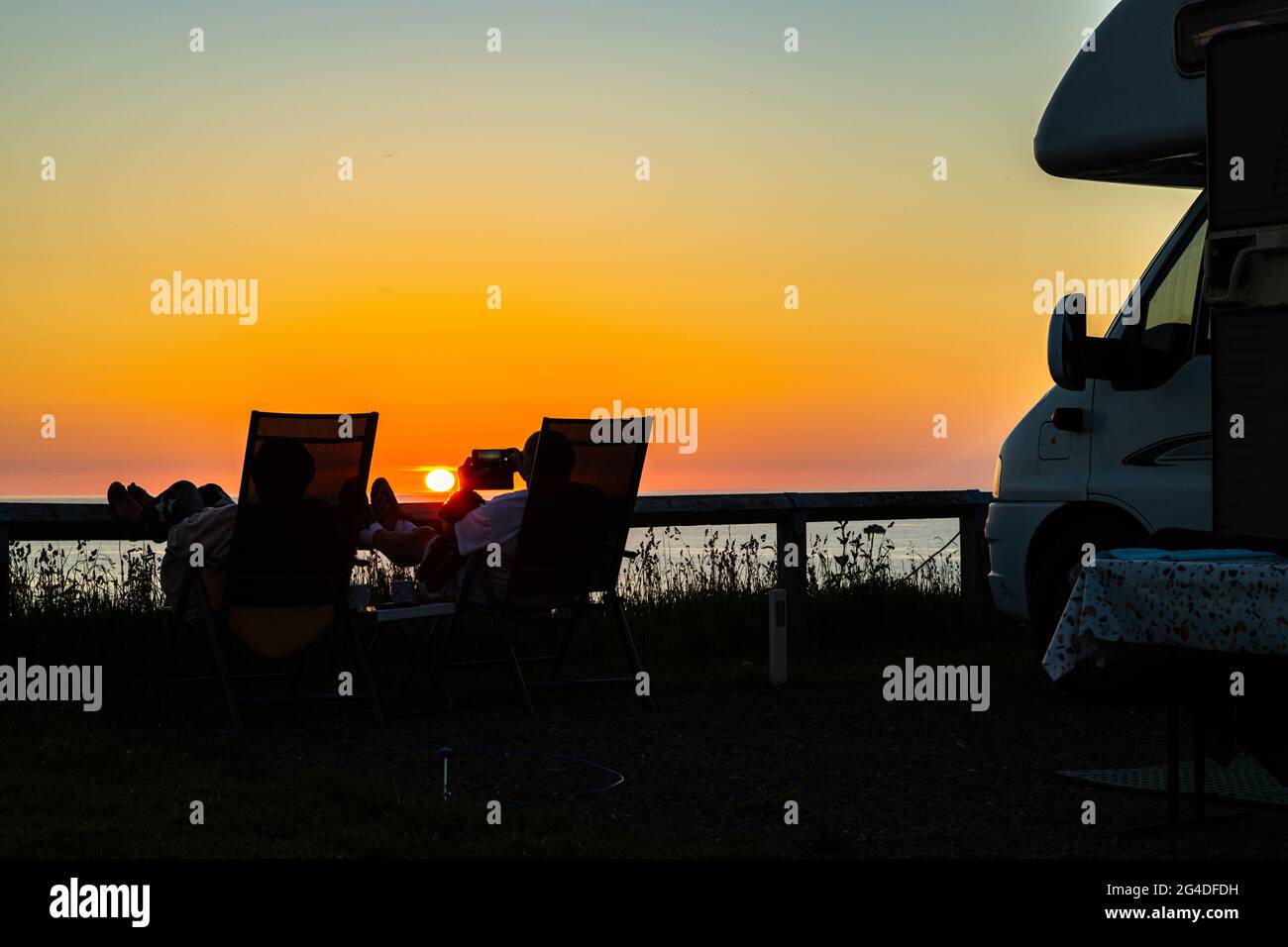 Magnifique coucher de soleil de l'heure d'or avec un couple se relaxant à côté d'un minibus de camping et profiter du coucher de soleil d'été à Cornwall Angleterre Royaume-Uni Banque D'Images Magnifique coucher de soleil de l'heure d'or avec un couple se relaxant à côté d'un minibus de camping et profiter du coucher de soleil d'été à Cornwall Angleterre Royaume-Uni Banque D'Images