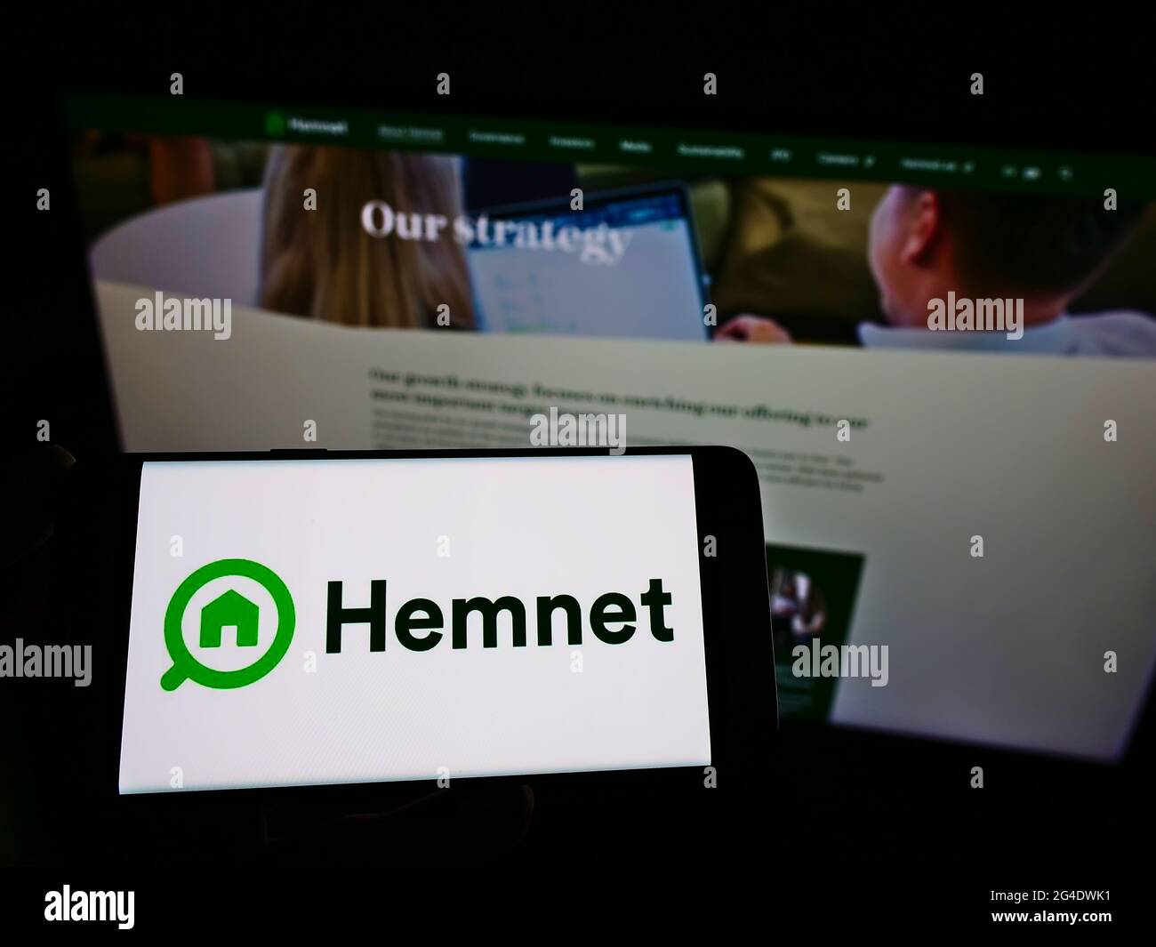 Personne tenant un téléphone portable avec le logo de la société suédoise de plate-forme immobilière Hemnet AB à l'écran en face de la page web. Concentrez-vous sur le centre de l'écran du téléphone. Banque D'Images
