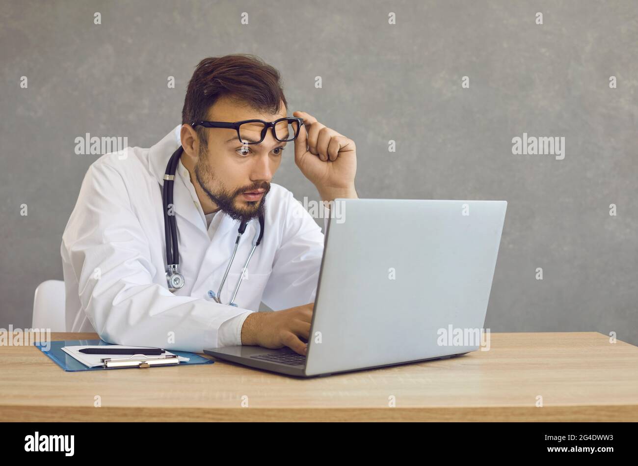 Un médecin masculin avec une expression choquée et confuse regarde un écran d'ordinateur portable voyant une erreur médicale. Banque D'Images