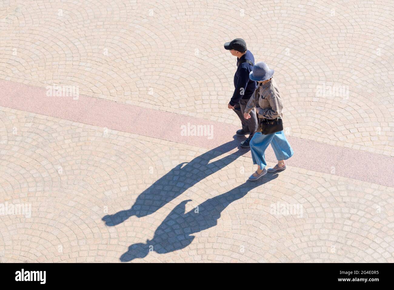 Un couple asiatique plus âgé a jeté de longues ombres en traversant la piste de l'Opéra de Sydney un matin ensoleillé en Nouvelle-Galles du Sud, en Australie Banque D'Images