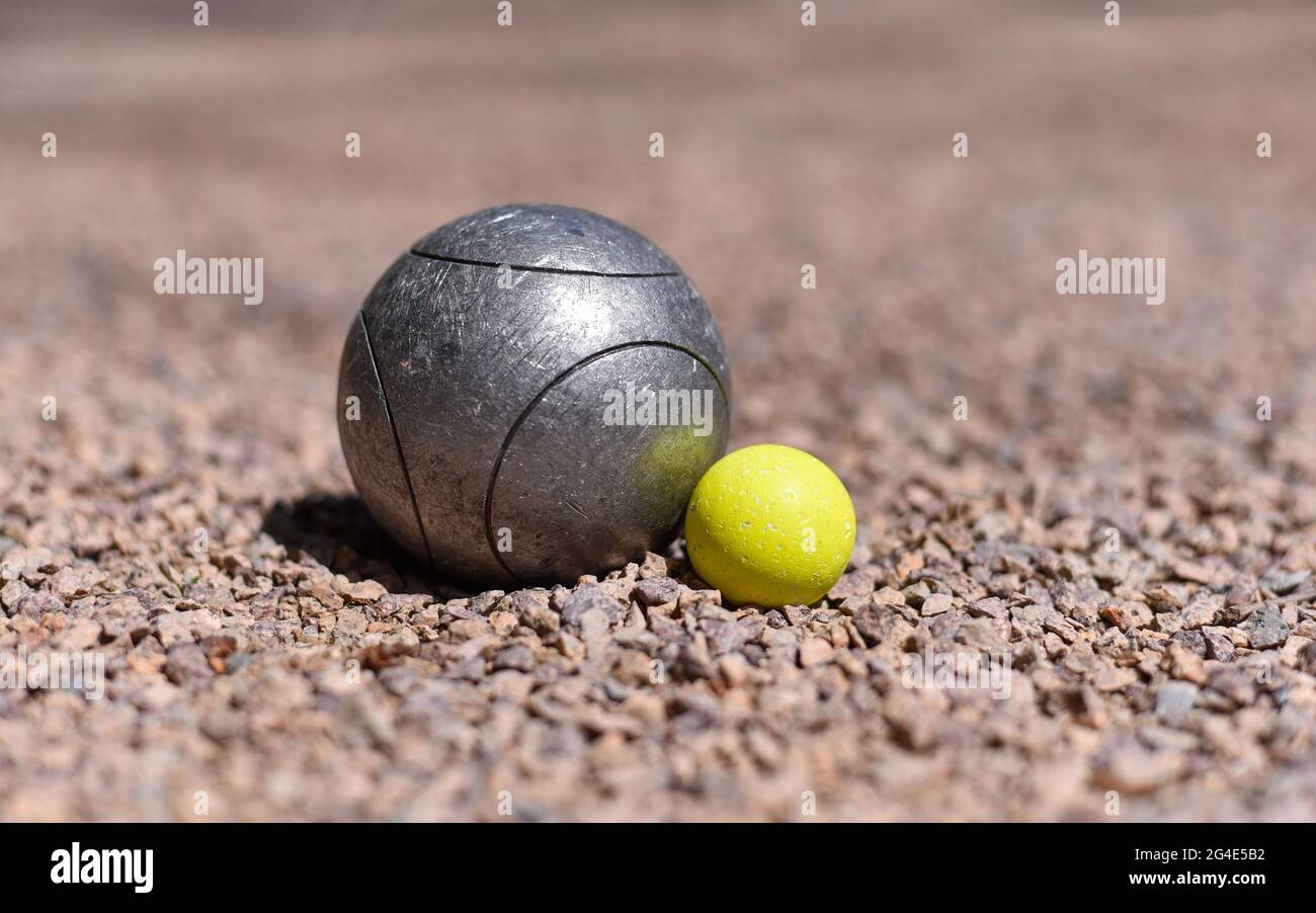 Une boule de pétanque (boule) à proximité d'une balle cible de cric jaune  sur un terrain de pétanque en gravier rose Photo Stock - Alamy