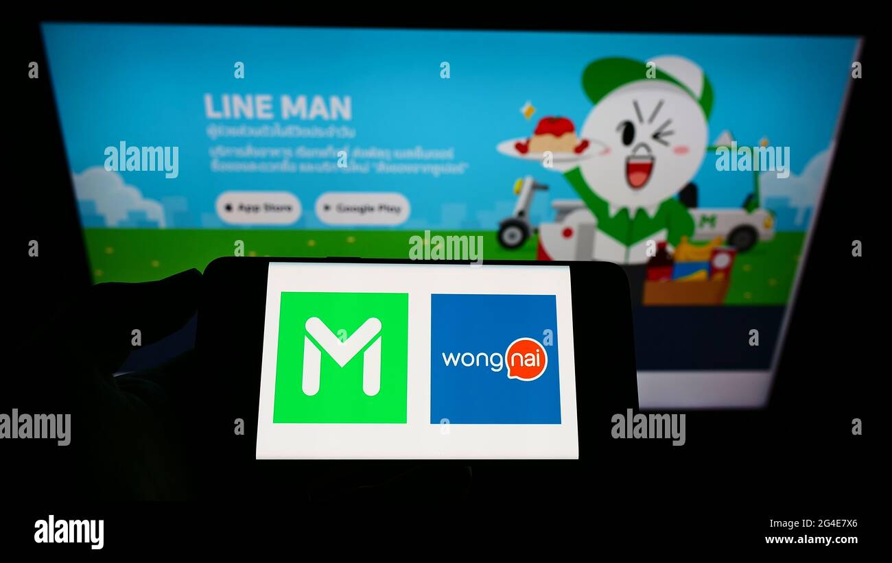 Personne tenant un smartphone avec le logo de la compagnie thaïlandaise de livraison de nourriture ligne HOMME Wongnai sur l'écran devant le site Web. Mise au point sur l'affichage du téléphone. Banque D'Images