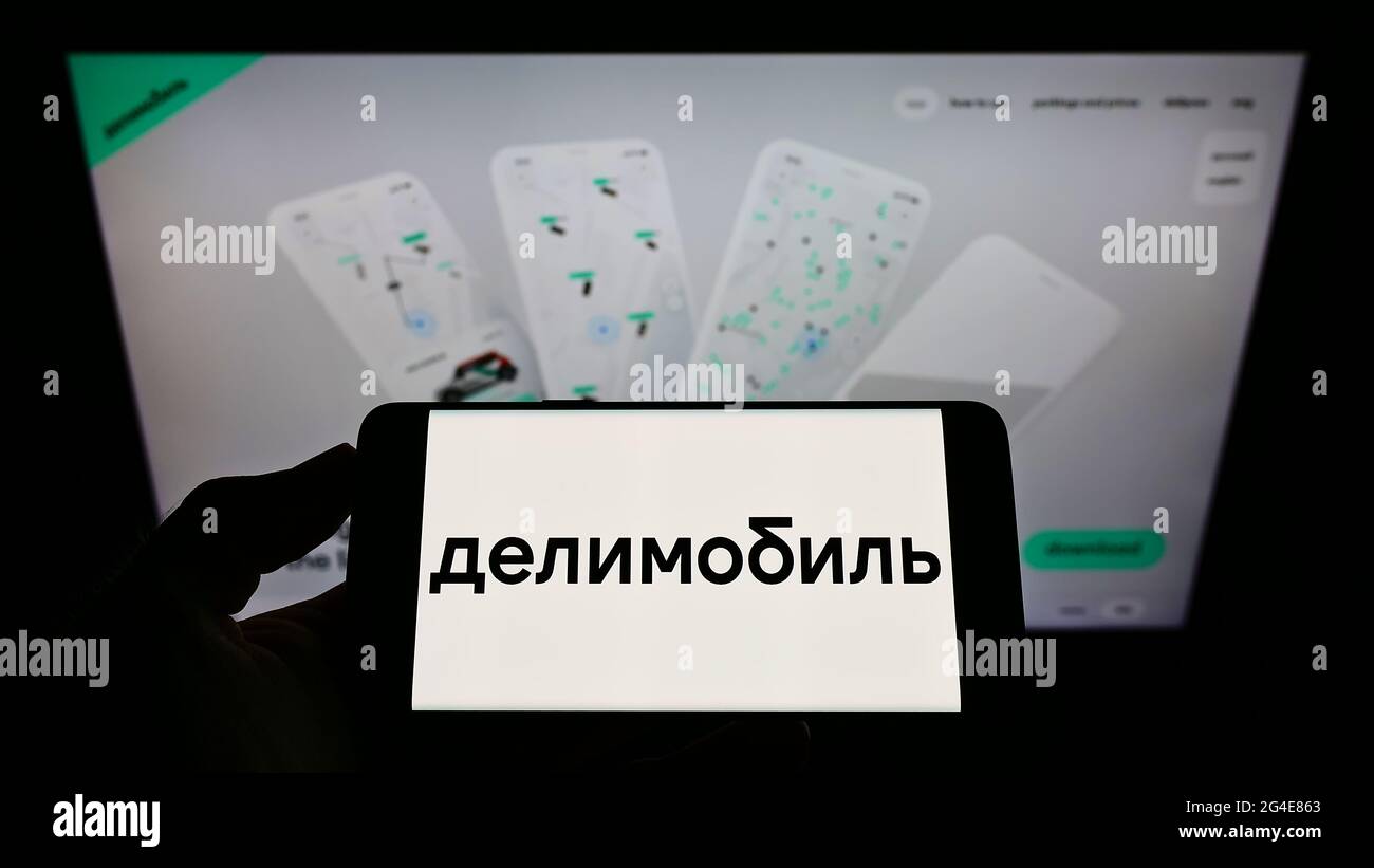 Personne tenant un smartphone avec le logo de la société russe de partage de voitures Delimobil sur l'écran devant le site Web. Mise au point sur l'affichage du téléphone. Banque D'Images