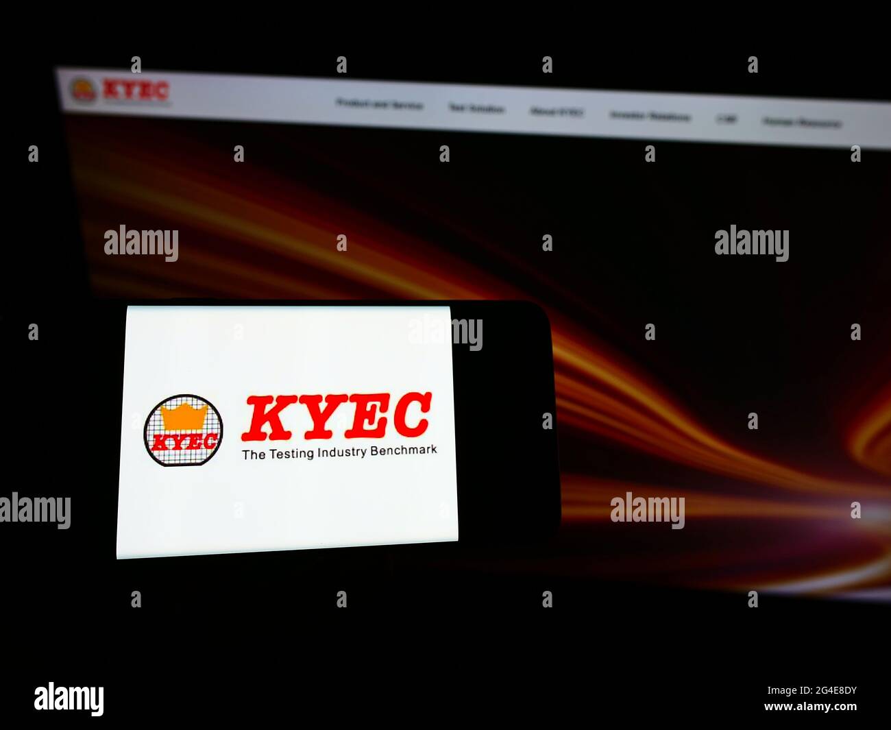 Personne tenant un téléphone portable avec le logo de la société taïwanaise King Yuan Electronics Corp. (KYEC) à l'écran devant la page Web. Mise au point sur l'affichage du téléphone. Banque D'Images