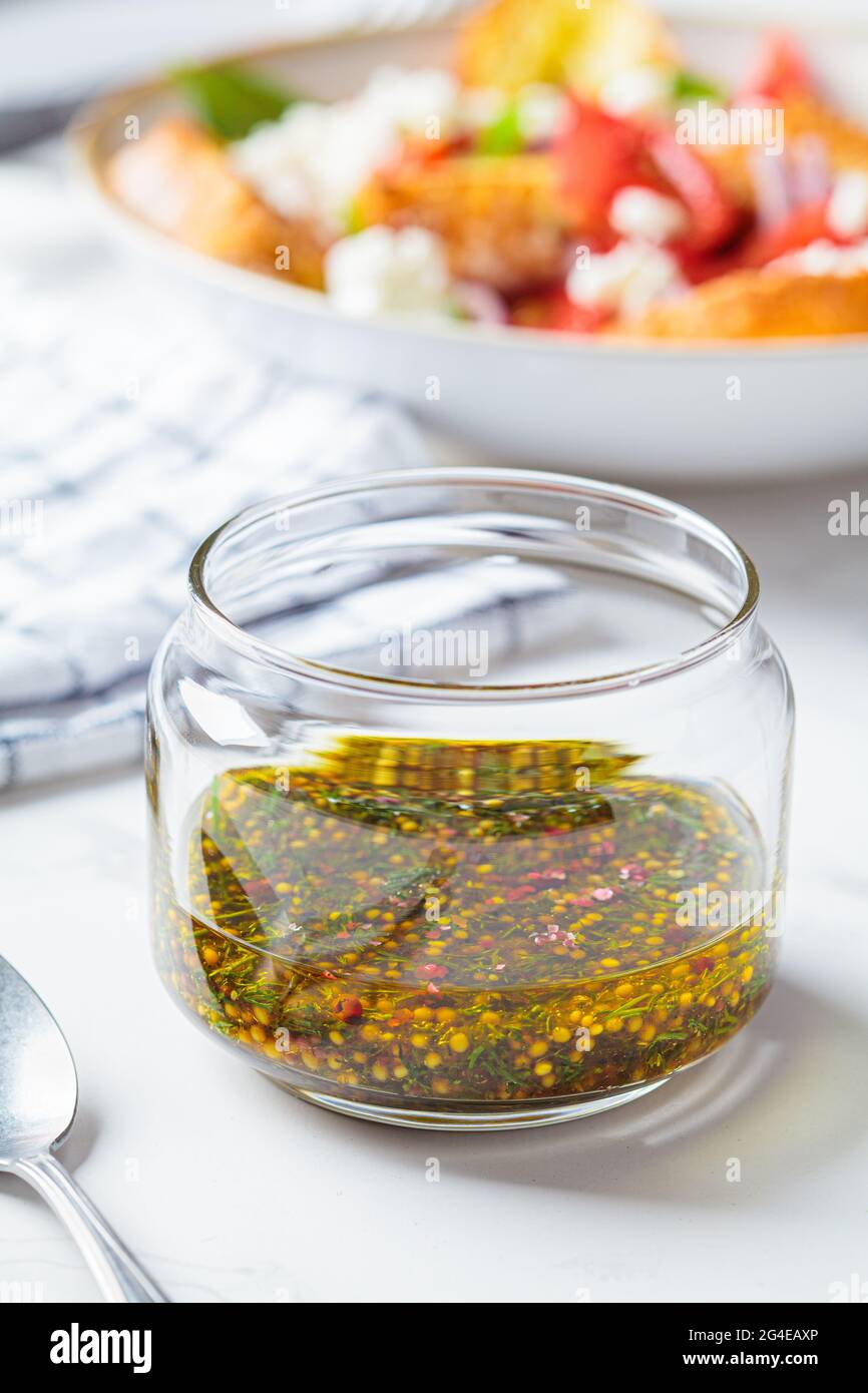Vinaigrette à la moutarde, à l'huile d'olive et à l'aneth dans un pot en verre. Cuisine saine concept. Banque D'Images