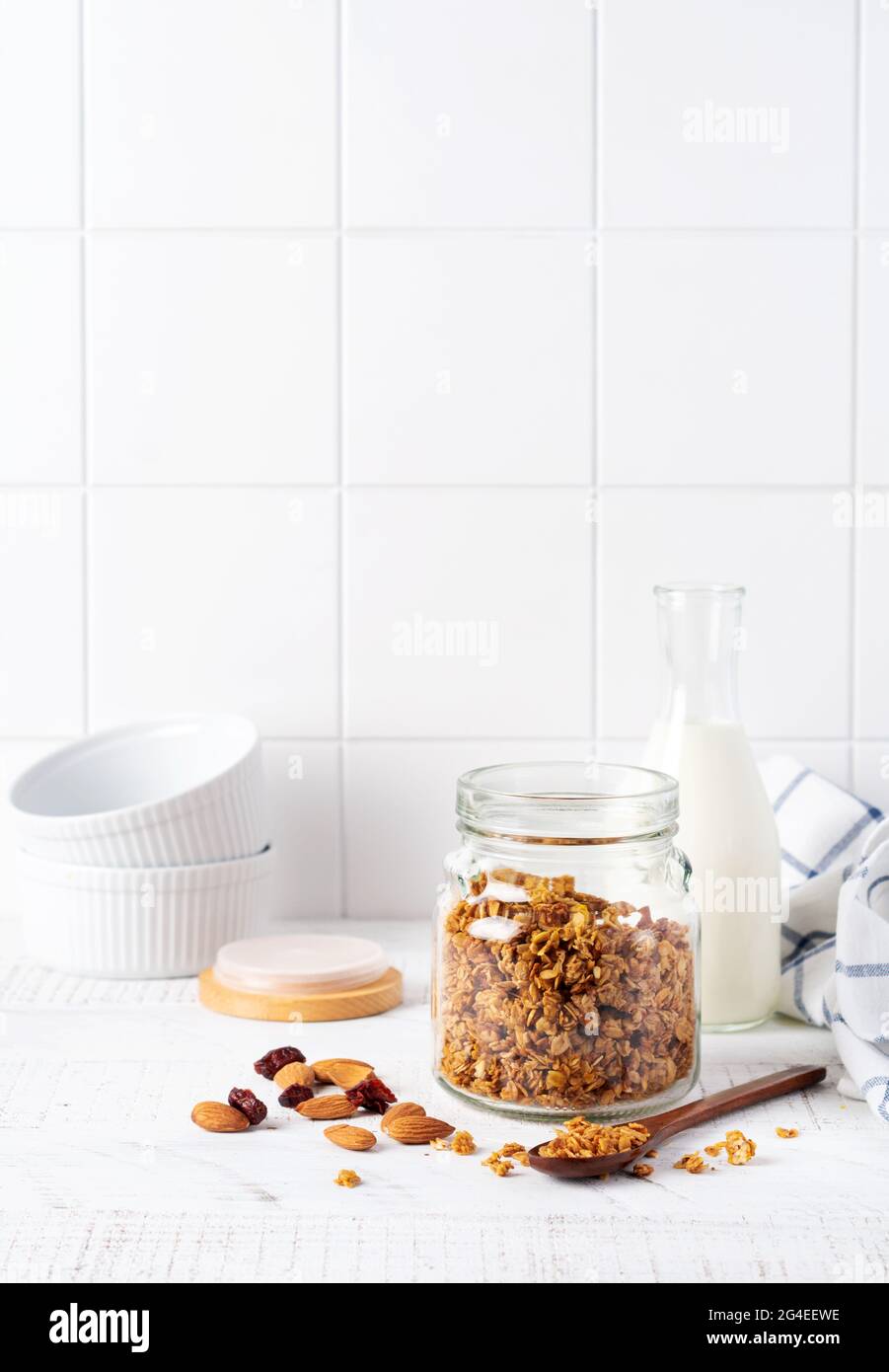 Faire une avoine de granola avec des noix et des fruits secs pour préparer un petit déjeuner sain sur une table lumineuse de cuisine. Style scandinave blanc. Mise au point sélective Banque D'Images