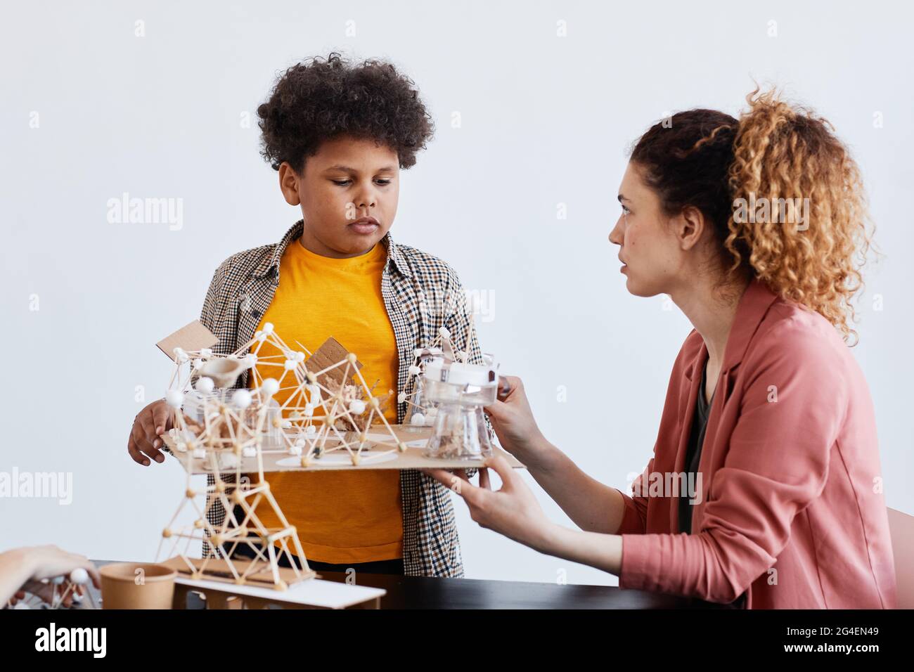 Portrait d'un jeune garçon présentant un projet scolaire à une enseignante pendant une leçon d'art et d'artisanat à l'école Banque D'Images