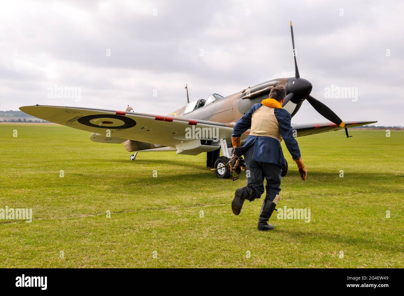 Reconstitution d'une bataille de Grande-Bretagne de la Seconde Guerre mondiale, avec un pilote de chasse de l'Armée de l'Air royale qui se dirige vers un Spitfire restauré du début de la guerre Banque D'Images