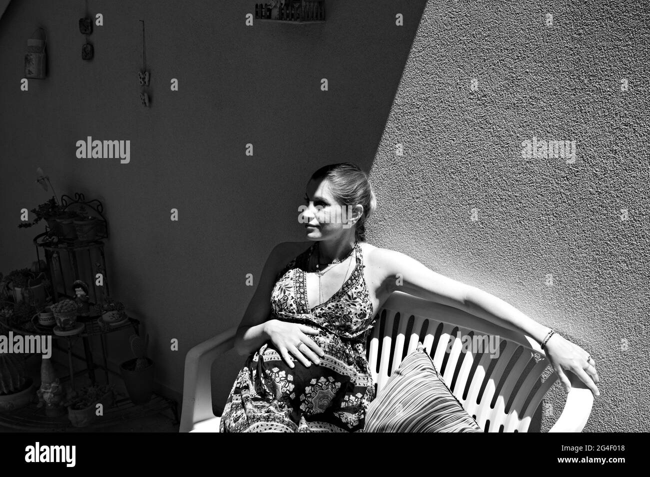 Une fille blonde enceinte avec une robe assise sur un banc dans le jardin le jour du printemps (Marche, Italie, Europe) Banque D'Images