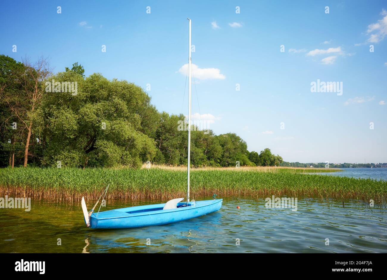 Petit voilier bleu amarré par des roseaux, Lac de Drawsko, Pologne. Banque D'Images Petit voilier bleu amarré par des roseaux, Lac de Drawsko, Pologne. Banque D'Images
