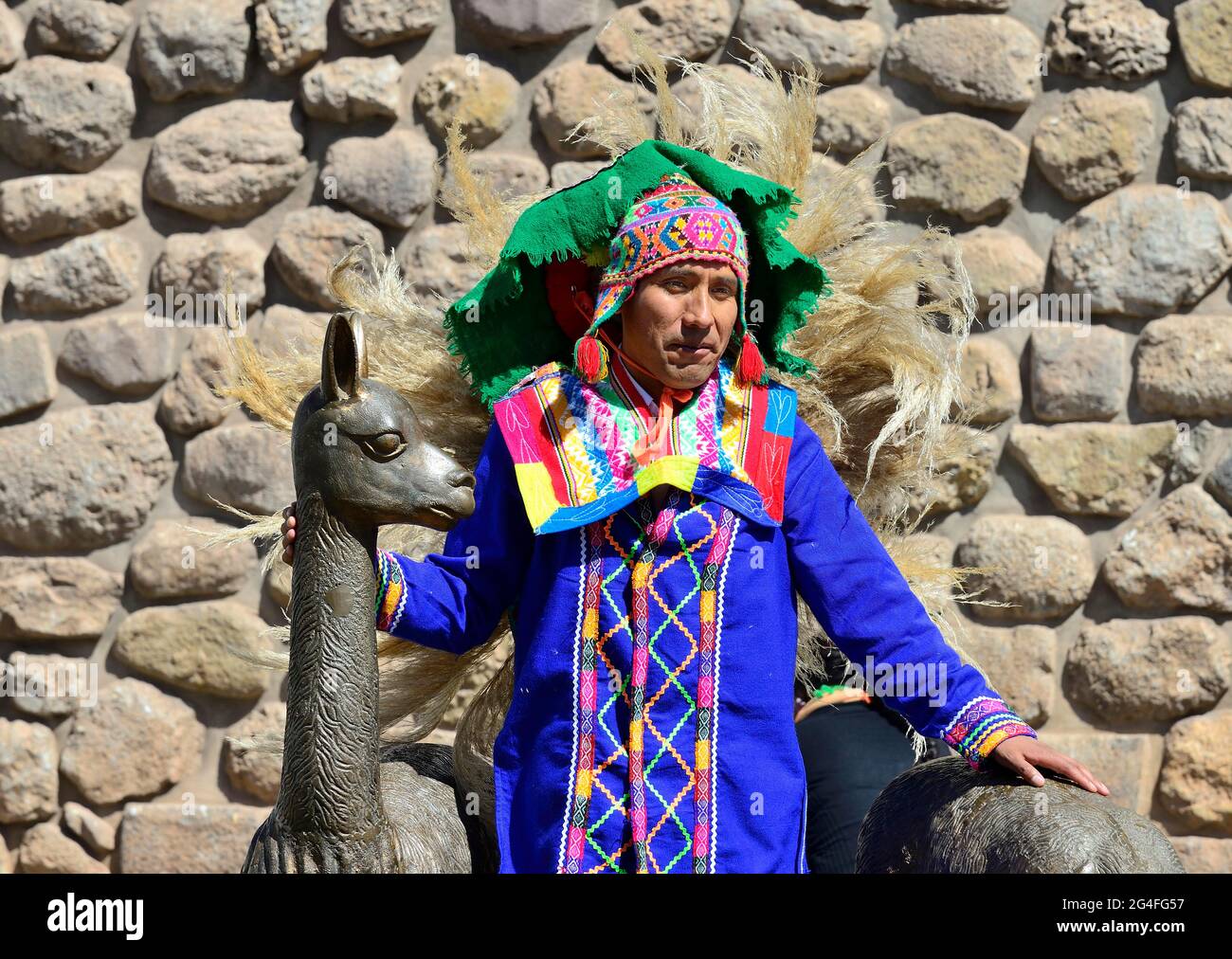 Homme indigène en costume traditionnel coloré devant un mur inca, Cusco, Pérou Banque D'Images
