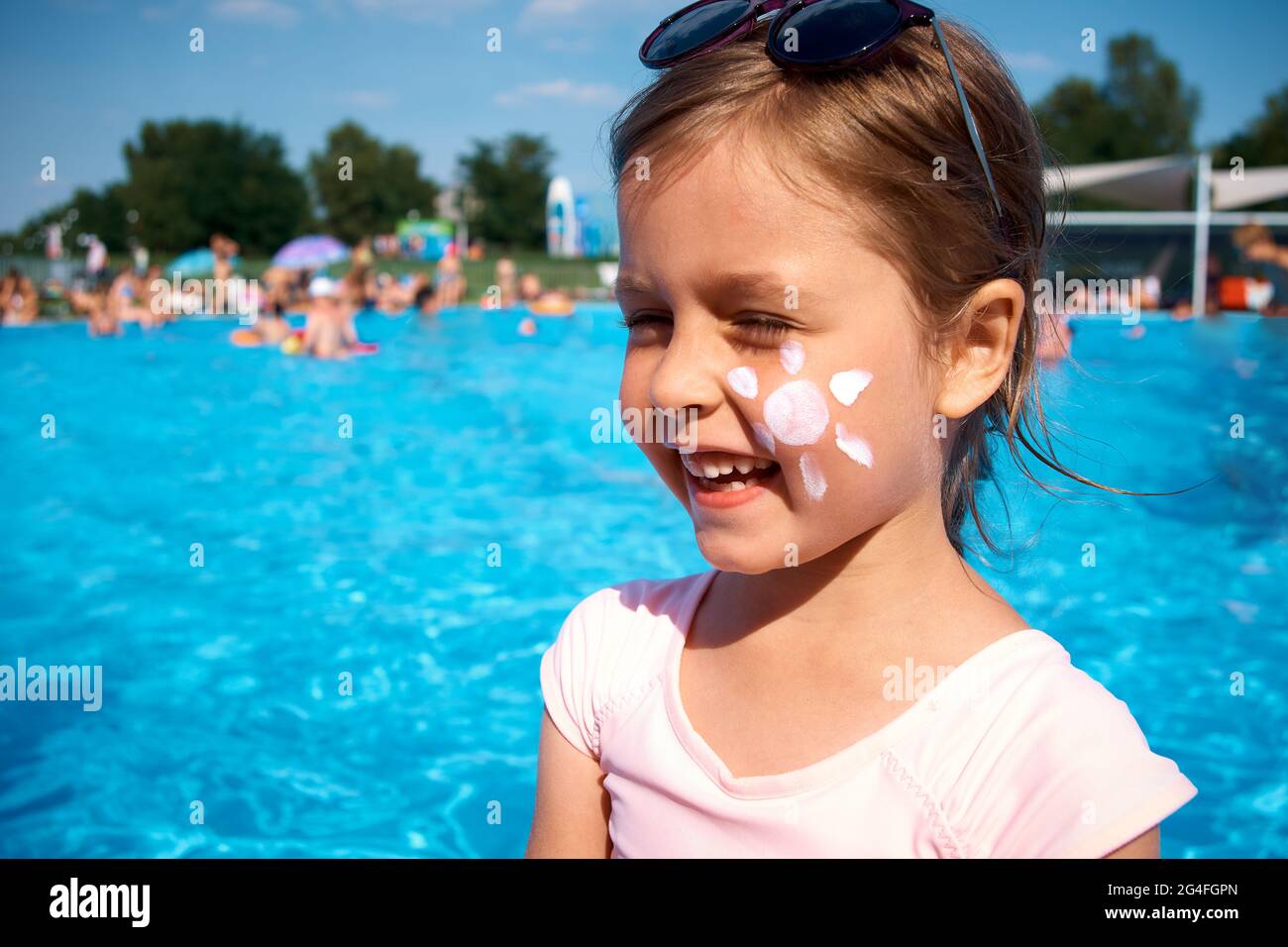 Une jolie petite fille à côté de la piscine avec le soleil de la crème sur  sa joue. Protection UV avec écran solaire. Publicité de creame SPF Photo  Stock - Alamy