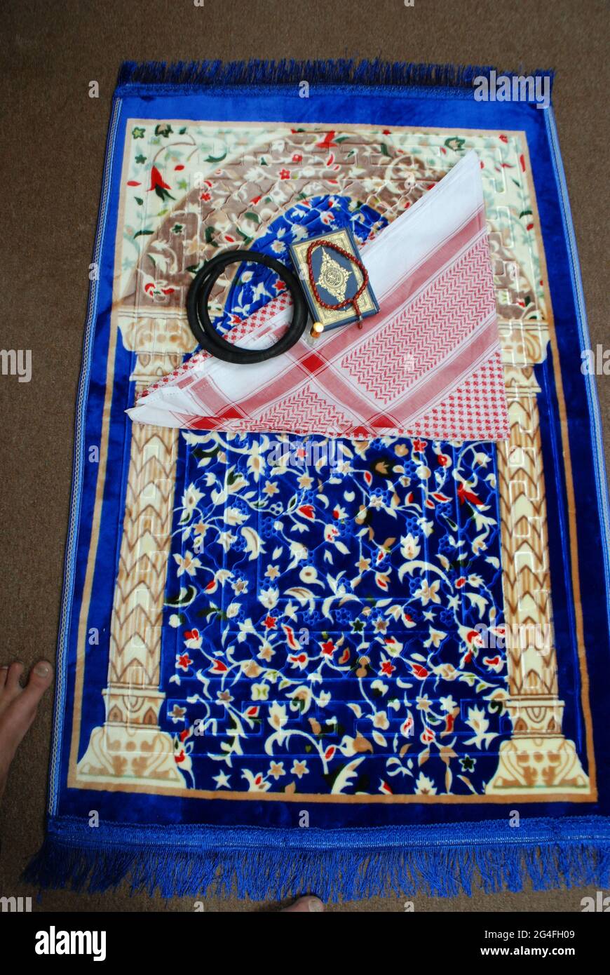 Islamique offrant prière accessoires traditionnels shémagh agal Saint Coran rossary perles parfum sur tapis coloré, Banque D'Images