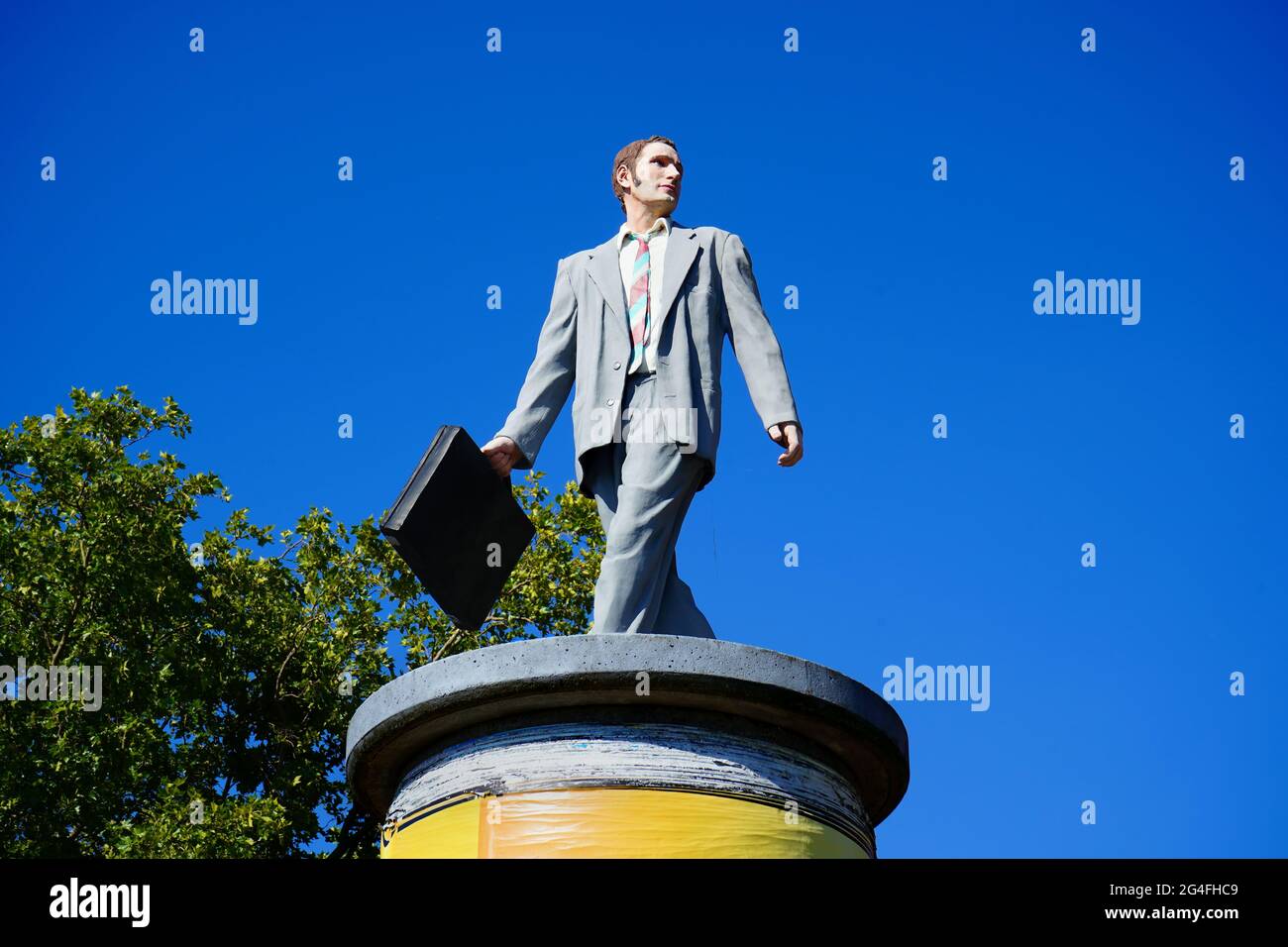 La sculpture d'art moderne grandeur nature 'homme d'affaires' de Christoph Pöggeler, debout sur une colonne publicitaire. Ces chabuvres sont appelées 'Säulenheilige'. Banque D'Images