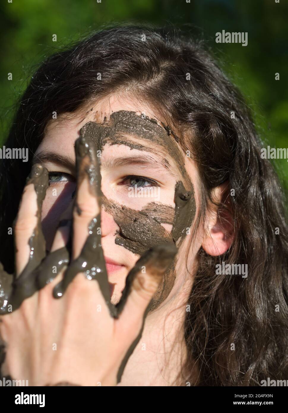 Visage boueux d'une jeune femme caucasienne à cheveux longs en plein air lors d'une Sunny Summer Day Banque D'Images