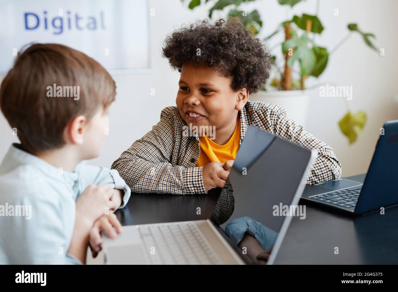Portrait d'un garçon afro-américain souriant qui parle à un ami pendant la classe à l'école Banque D'Images