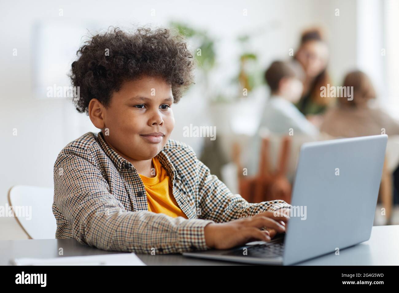 Portrait d'un jeune garçon afro-américain souriant utilisant un ordinateur portable en classe, espace de copie Banque D'Images