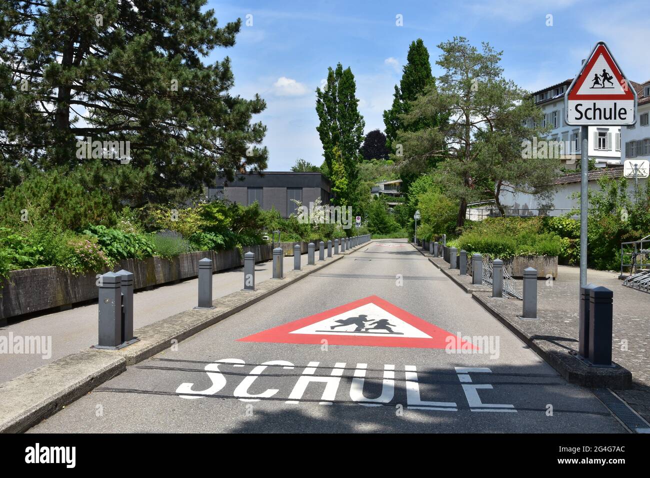 Panneau d'avertissement sur une route et panneau de signalisation vertical sur le chemin de l'école en langue allemande en Suisse. Le panneau de signalisation est triangle rouge avec les enfants en train de courir i Banque D'Images