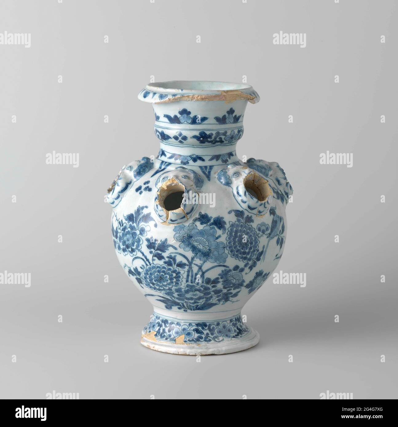. Porte-fleurs de faïence peinte en bleu. Le vase se compose de deux vases ensemble, dont le fond est grand et canopé et le haut petit et sphérique. Chaque vase a un pied rond. Sur les épaules de chaque vase, des têtes d'ange soufflantes étaient présentes en relief, clignotantes de dont les monticules. Ces taches ont été décomposées sur les deux vases. Les vases sont chacun peints avec des fleurs sur et sur les rochers et les oiseaux (O.A. Pauwen). Banque D'Images